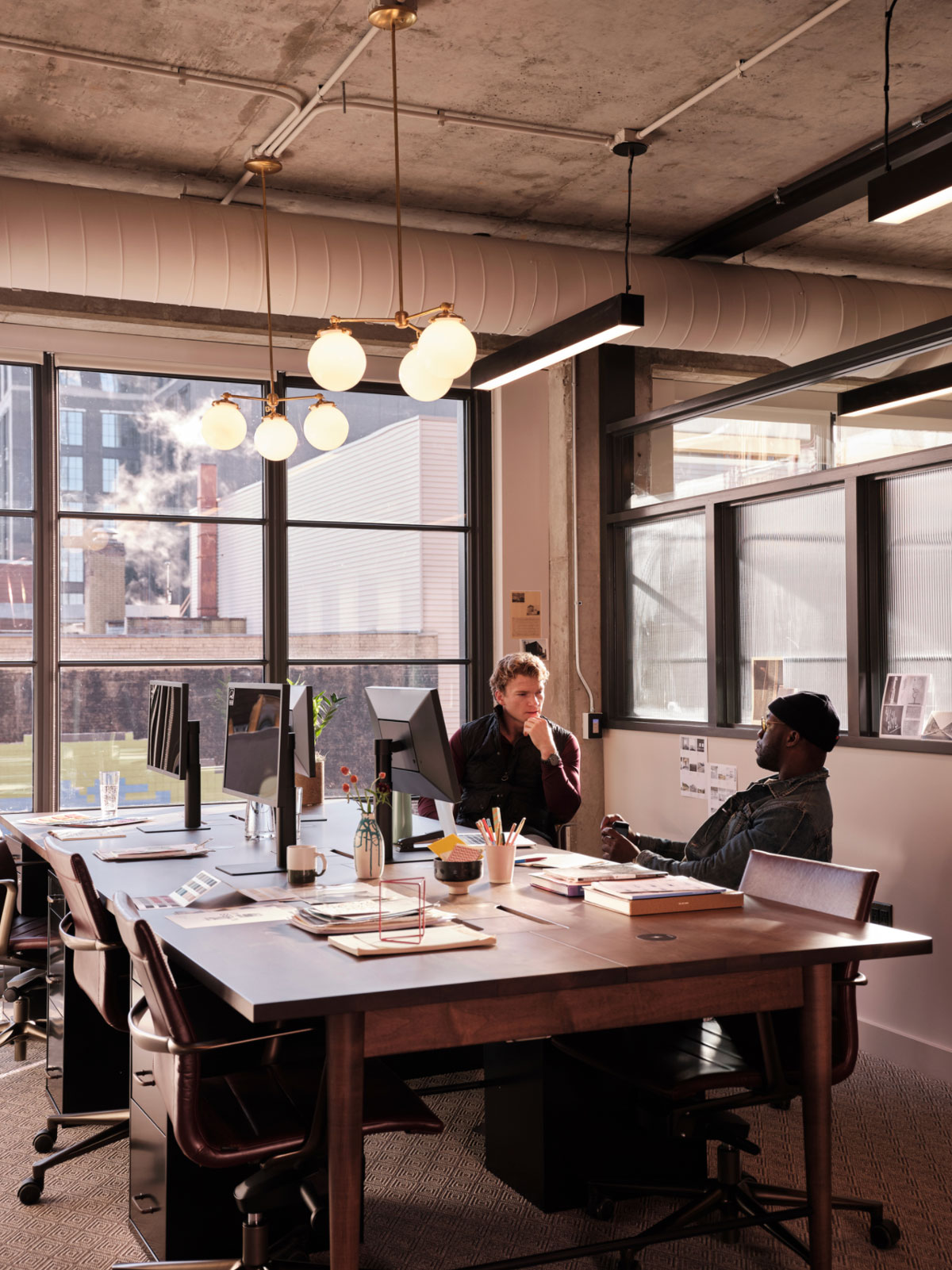 Two people sit at a large desk in an office