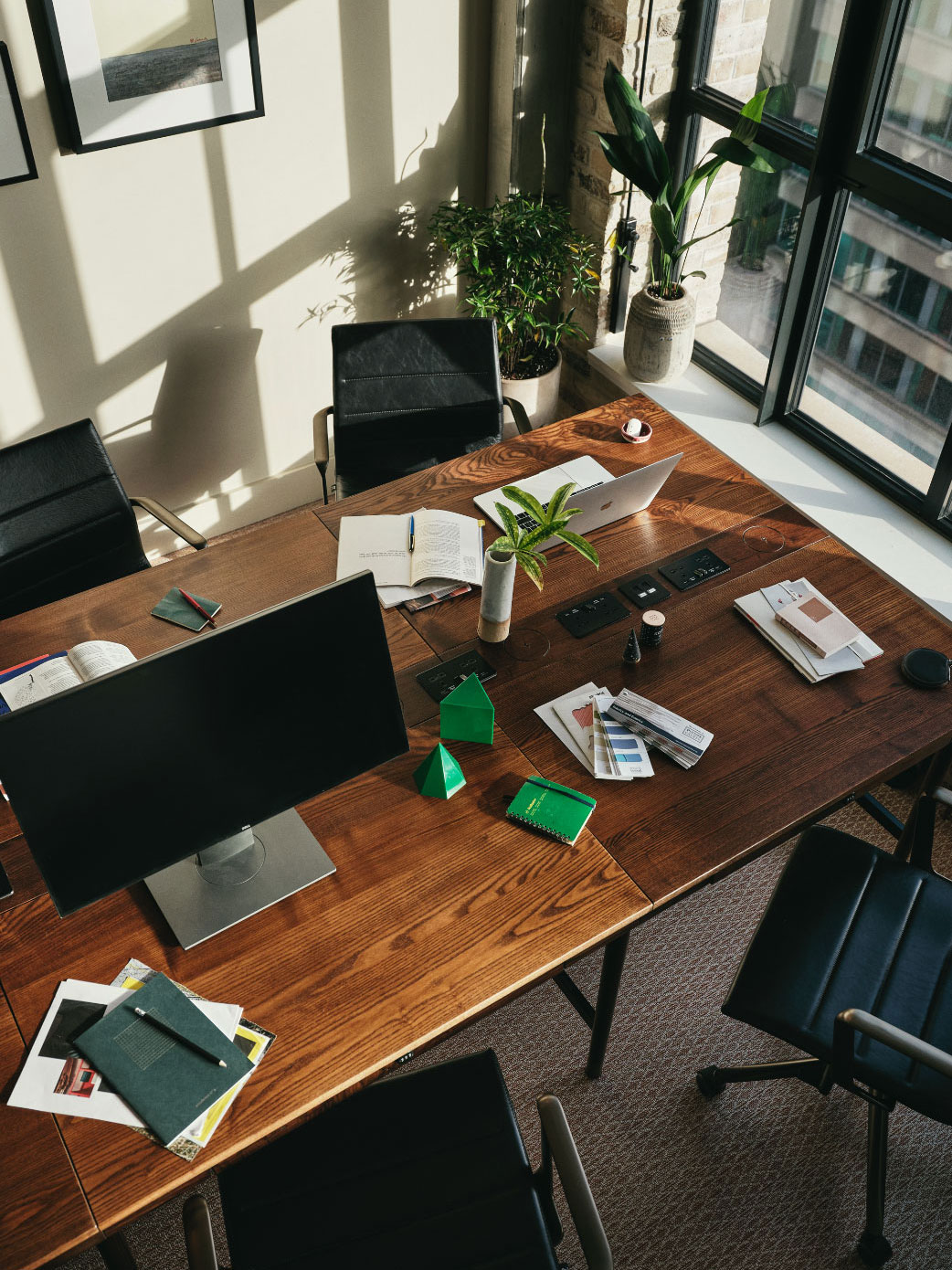 Desks with computer monitor and notebooks with sunlight streaming in the window