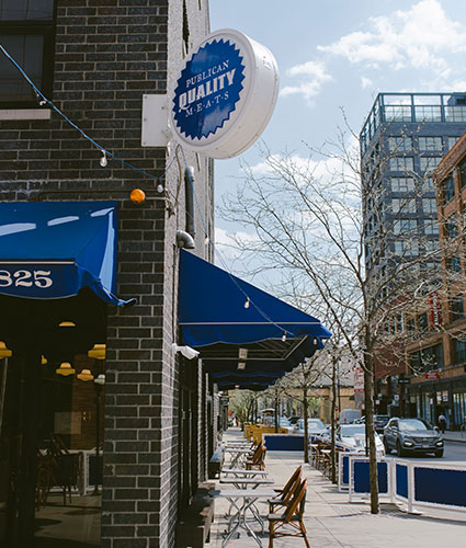 Publican Quality Meats sign on the corner of the building, with outside seating on the pavement