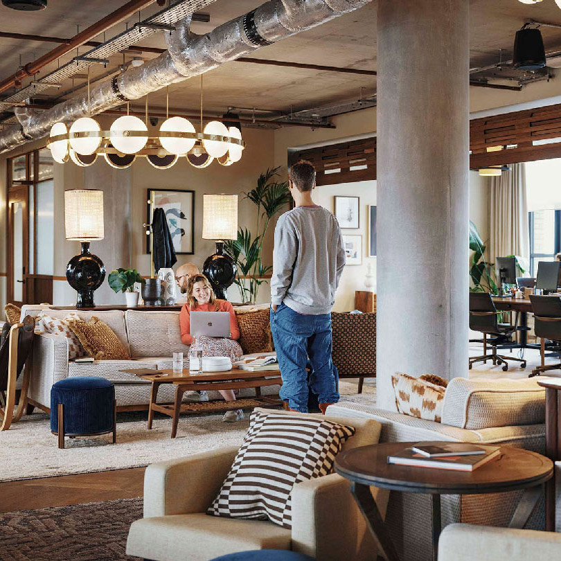 Two people talking in the sofa area between open studios