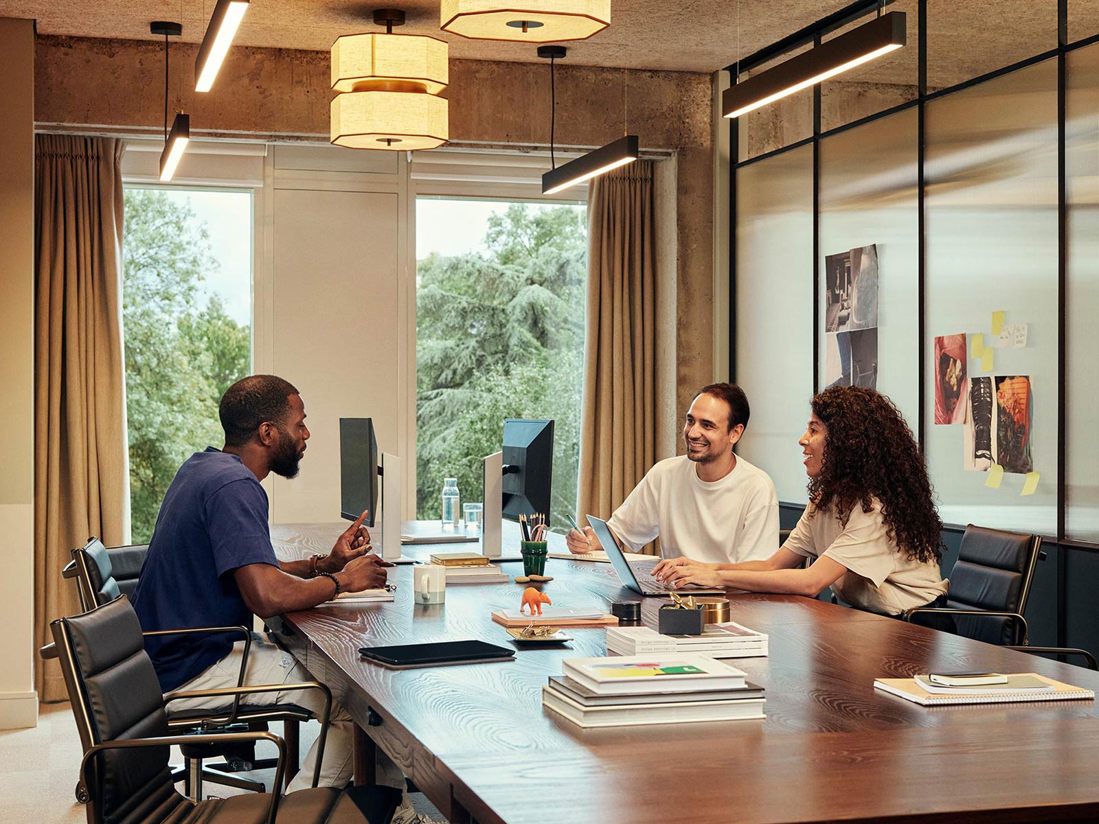 Workers chat at an open studio space with stylish wooden table between them