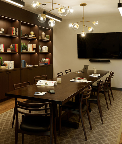 Library space with long table and monitor on the wall, plus bookshelf