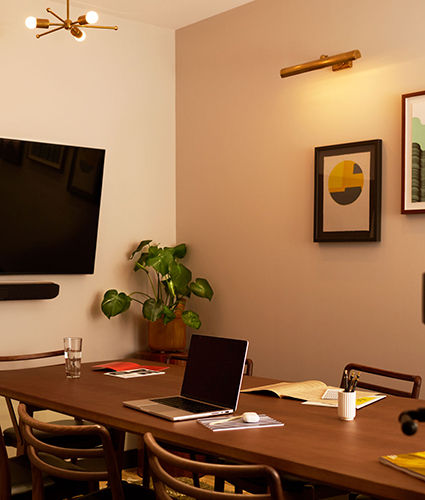 Desk with laptop on it and monitor on wallalso visible