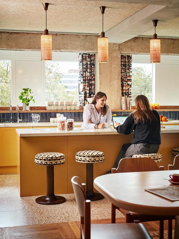 Two people at the pantry, leaning over the kitchen-counter with bar stools.