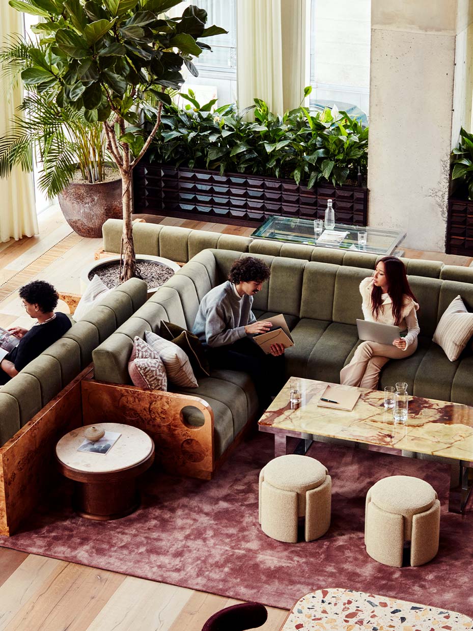 people sitting in L shape sofa with a table in front of them. and 2 pouffes.