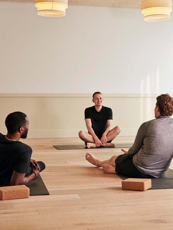 The wellness studio with 3 people on yoga mats with bricks.