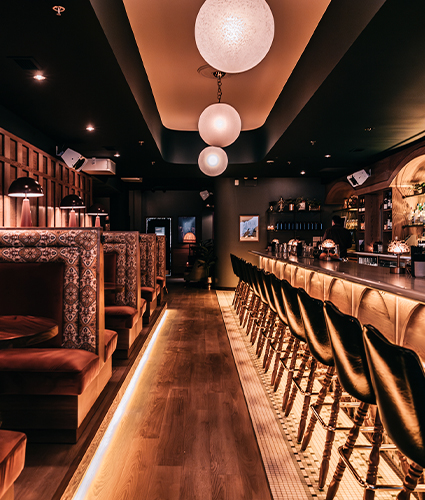 Bisous interior showcasing bar with a line of chairs and booths.
